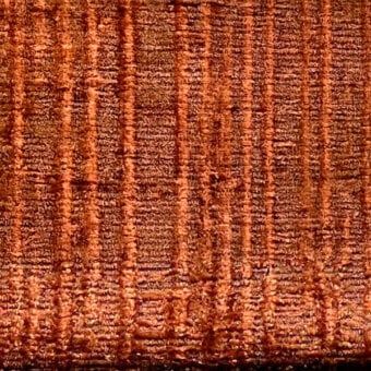 Reddish-brown woven fabric texture with vertical stripes, a rough granular surface, and mottled tonal variations; “egoitaliano > fabric (d) > marlys” text.